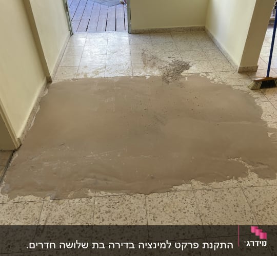 רצפה עם שכבת חומר חום, מטאטא בצד ימין